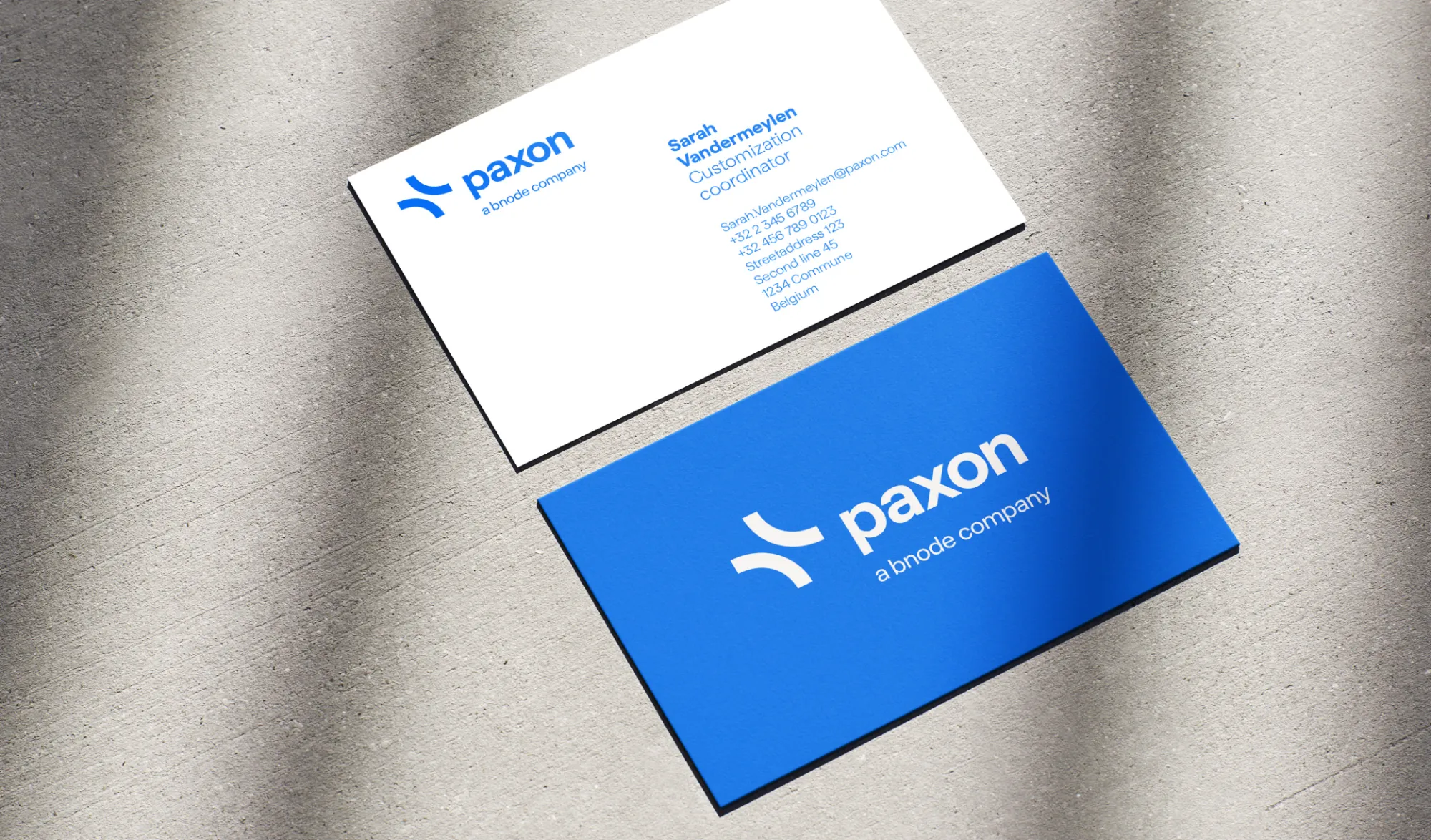 Paxon business cards in white and blue, with the logo and “a bnode company”